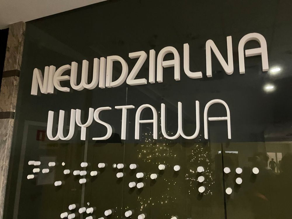 The Invisible Exhibition sign in Warsaw, with braille dots below the letters
