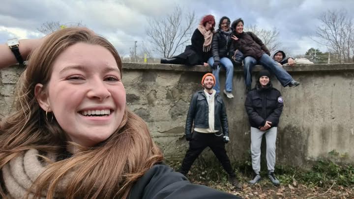 A group of friends on and in front of a stone wall