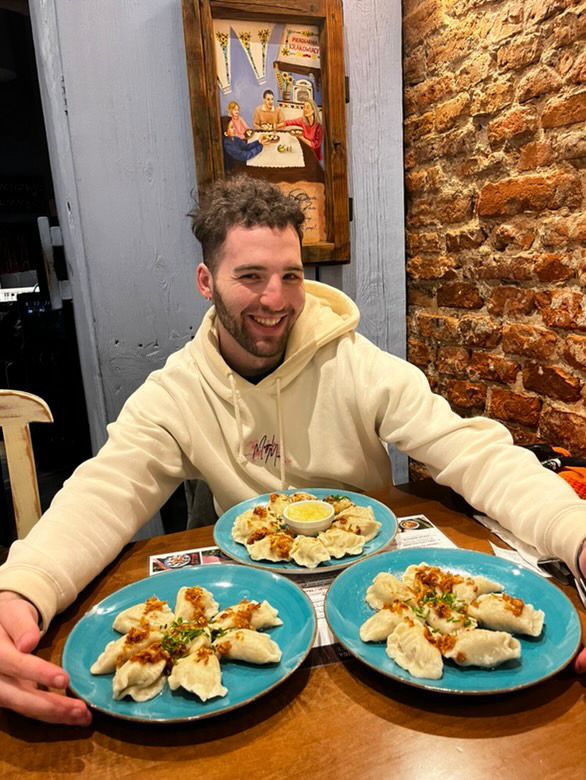 Brandon smiling behind three plates of pierogi