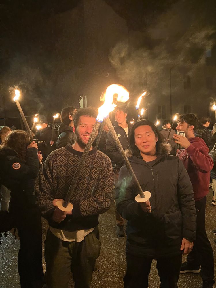 Brandon and a friend holding lit torches at night in a crowd